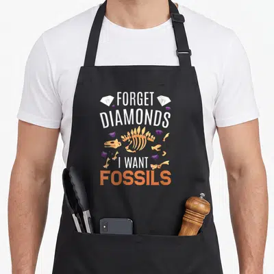 Tablier de cuisine noir avec inscription Forget Diamonds I Want Fossils et squelette de dinosaure orange.