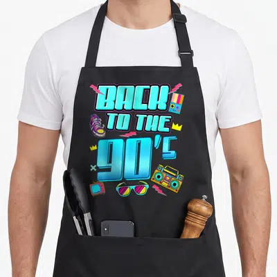 Tablier de cuisine noir avec inscription Back to the 90s et accessoires colorés style années ninety.