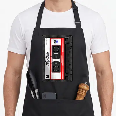 Tablier de cuisine noir avec illustration détaillée d'une cassette mixtape rouge et blanche aux accents années 90.