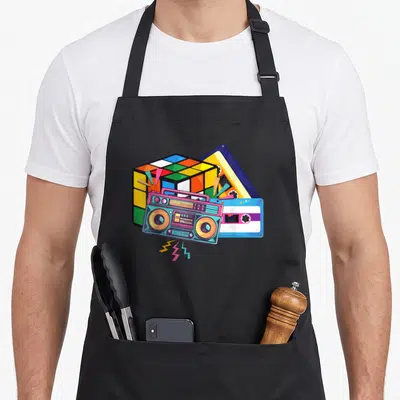 Tablier de cuisine noir avec illustration d'une cassette, d'un boombox et d'un cube Rubik colorés.