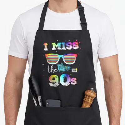 Tablier de cuisine noir avec lunettes rainbow, sneakers bleues, cassette audio et texte I Miss The 90s en dégradé coloré.