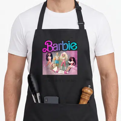 Tablier de cuisine noir avec illustration Barbie Team Années 80 et texte humoristique sur les bas de laine.