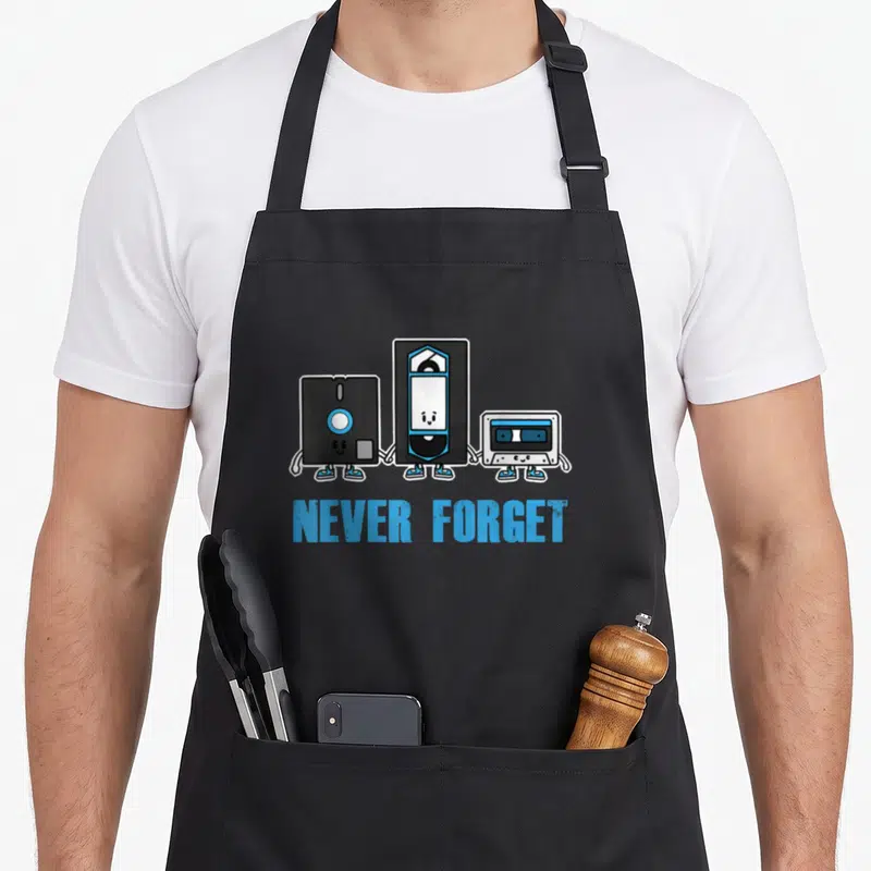 Tablier de cuisine noir avec une cassette, une VHS et une disquette anthropomorphes tenant la main sous le texte Never Forget en bleu.
