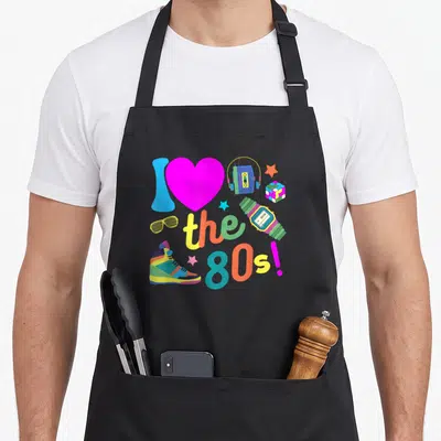 Tablier de cuisine noir avec cœur rose, cassette audio, cube Rubik et sneakers colorées style années 80.