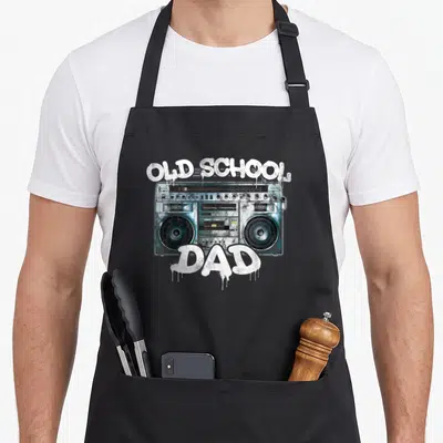 Tablier de cuisine noir avec illustration boombox vintage et texte Old School Dad en style graffiti blanc coulant.