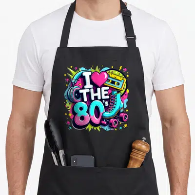 Tablier de cuisine noir avec illustration colorée I Love The 80s incluant des patins et une cassette audio.