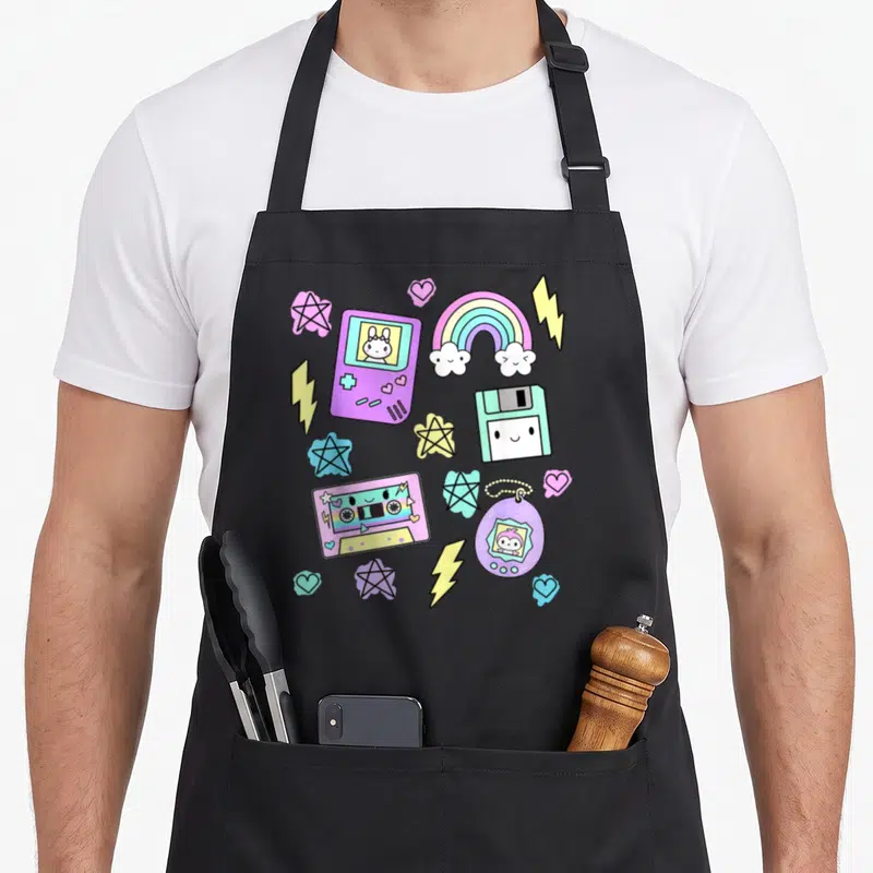 Tablier de cuisine noir avec illustrations colorées de cassette, console, rainbow et tamagotchi style kawaii.