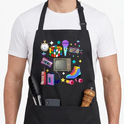 Tablier de cuisine noir avec illustration colorée de casses, rubik, micro et roller vintage.