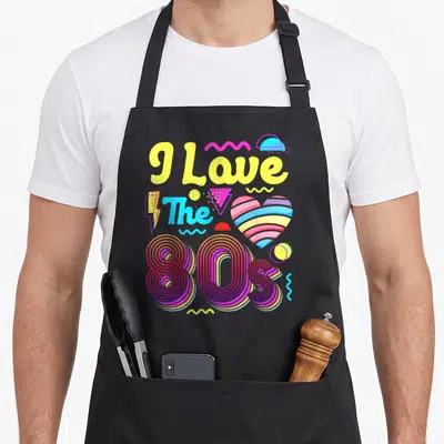 Tablier de cuisine noir avec le texte I Love The 80s en lettres jaunes et un cœur aux bandes arc-en-ciel.