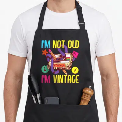 Tablier de cuisine noir avec illustration de cassette audio et texte I'm Not Old I'm Vintage multicolore.