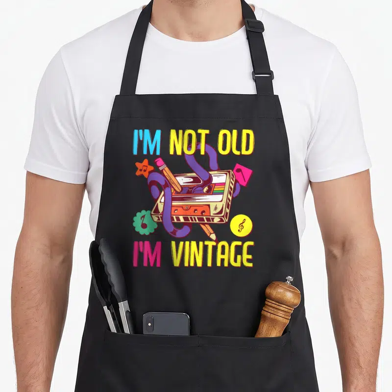Tablier de cuisine noir avec illustration de cassette audio et texte I'm Not Old I'm Vintage multicolore.