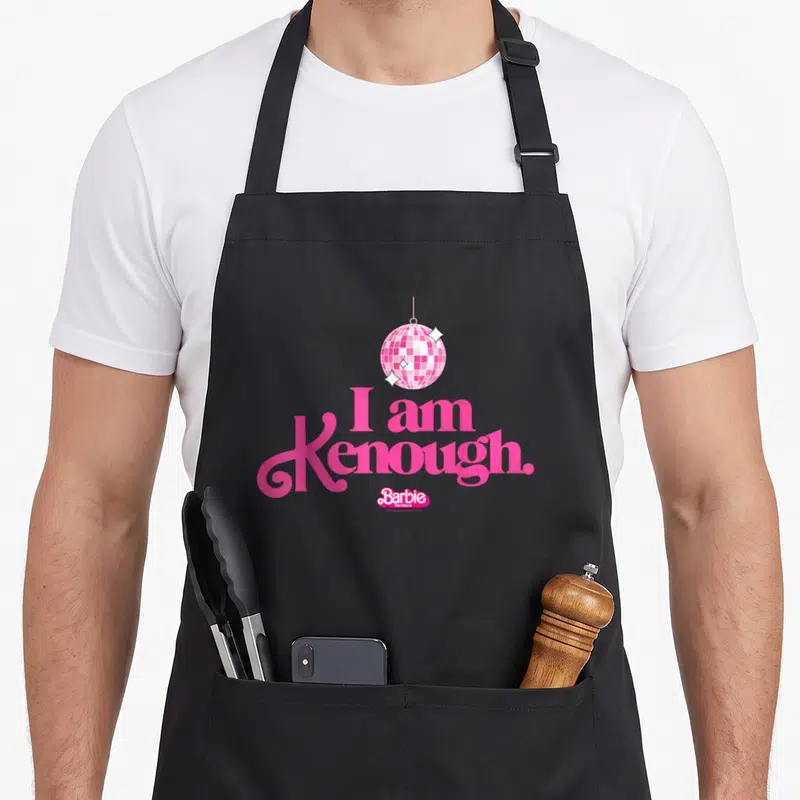 Tablier de cuisine noir avec une boule disco rose et le texte I am Kenough en lettres roses stylisées.
