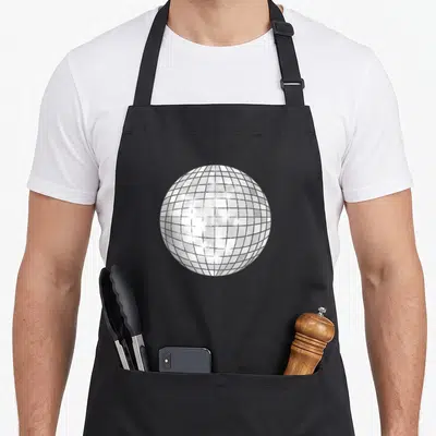 Tablier de cuisine noir orné d'une illustration centrale représentant une boule à facettes argentée aux reflets lumineux typique des discothèques des années 1970.