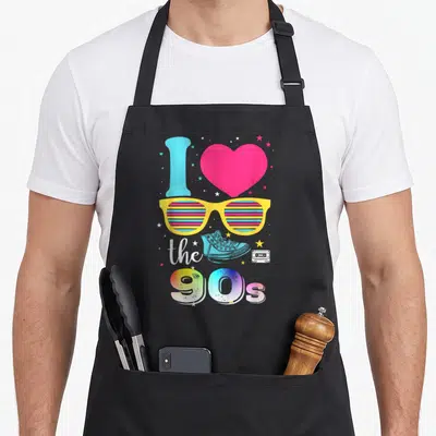 Tablier de cuisine noir avec lunettes jaunes, cœur rose et texte J'aime les 90s coloré.