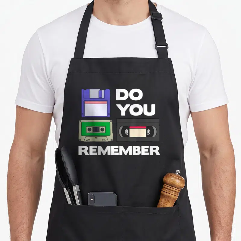 Tablier de cuisine noir avec illustration de disquette, cassette audio, bande VHS et texte Do You Remember en blanc.