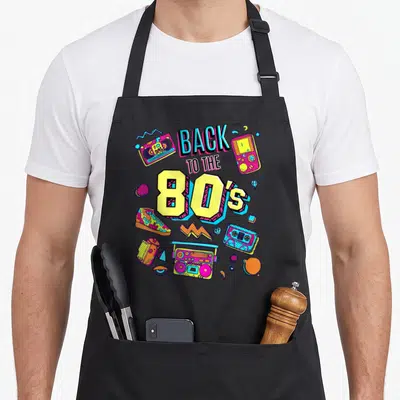 Tablier de cuisine noir avec illustration colorée Back to the 80's incluant boombox, cassette et sneaker.