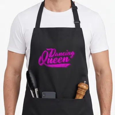 Tablier de cuisine noir avec inscription Dancing Queen en lettres roses vives style calligraphie rétro des années septante.