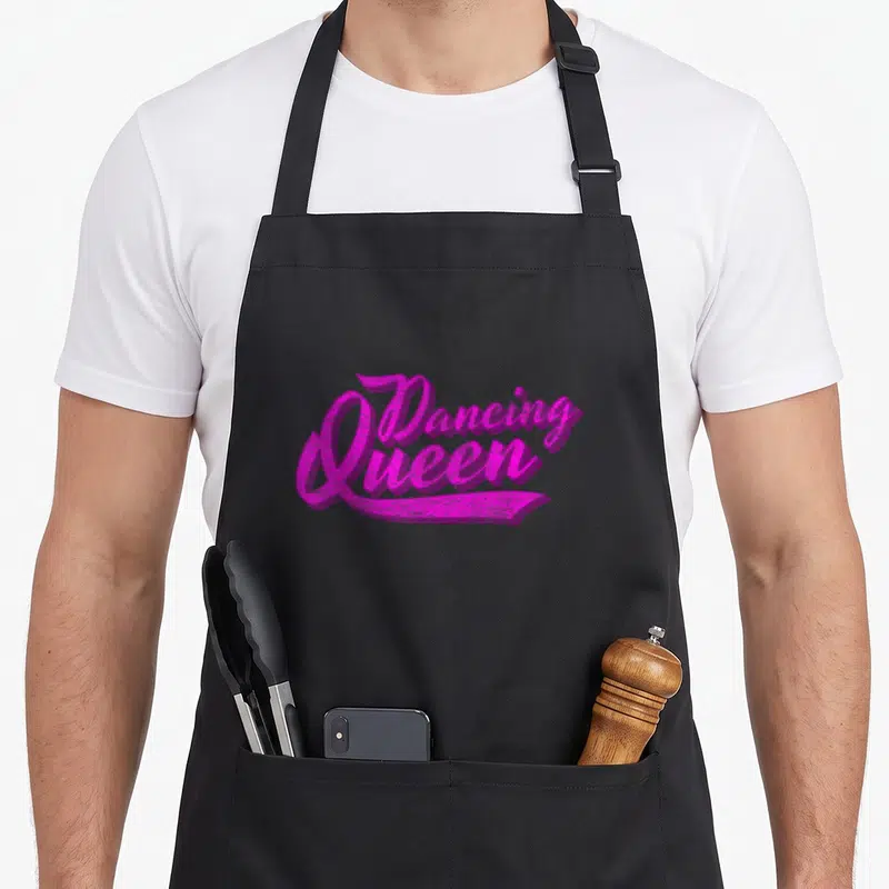 Tablier de cuisine noir avec inscription Dancing Queen en lettres roses vives style calligraphie rétro des années septante.