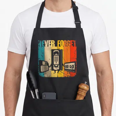 Tablier de cuisine noir avec illustration vintage disquette VHS et cassette sur fond rayé multicolore.