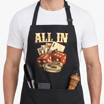 Tablier de cuisine noir avec illustration All In, cartes à jouer, dés rouges et pièce d'argent au dollar.