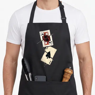 Tablier de cuisine noir avec un Jack et un As de Pique illustrés en style vintage et coupés par des traits blancs.