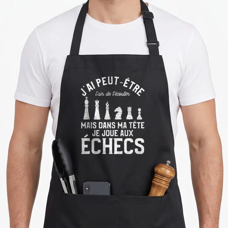 Tablier de cuisine noir avec une inscription blanche sur les échecs et six pièces stylisées en polygone alignées au centre.
