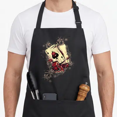 Tablier de cuisine noir avec illustration de dés démoniaques rouges et carte à jouer flambante.