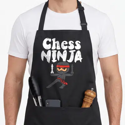 Tablier de cuisine noir avec illustration d'un ninja tenant une reine et un roi d'échecs sous le texte Chess Ninja.