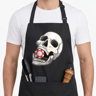 Tablier de cuisine noir avec illustration d'un crâne blanc tenant un jeton de poker rouge et blanc entre ses dents.