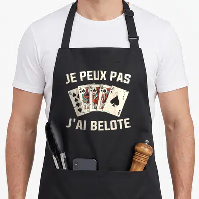 Tablier de cuisine noir avec illustration de cartes à jouer vintage et texte humoristique beige.
