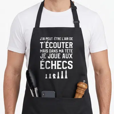 Tablier de cuisine noir avec le texte blanc J'ai peut-être l'air de t'écouter mais dans ma tête je joue aux échecs et des pièces d'échecs en dessous.