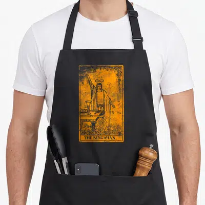 Tablier de cuisine noir avec illustration orange et grise d'une carte de tarot vintage représentant le Magicien.