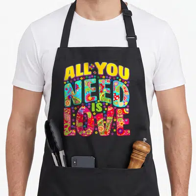 Tablier de cuisine noir avec inscription All You Need Is Love ornée de motifs floraux multicolores et d'ambiance flower power.