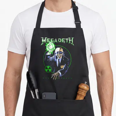 Tablier de cuisine noir avec illustration d'un crâne en costume tenant une flamme verte sous le logo Megadeth.