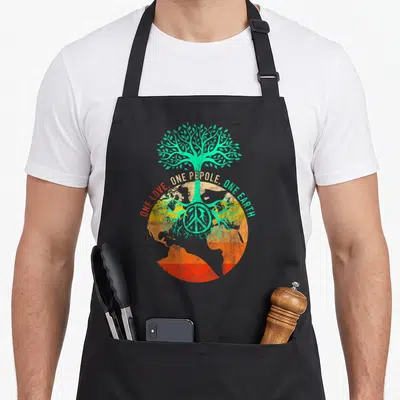 Tablier de cuisine noir avec un arbre vert sur un globe terrestre orange et un signe de paix au centre.