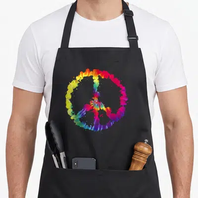 Tablier de cuisine noir avec un grand signe de paix coloré style éclaboussure tie dye au centre.