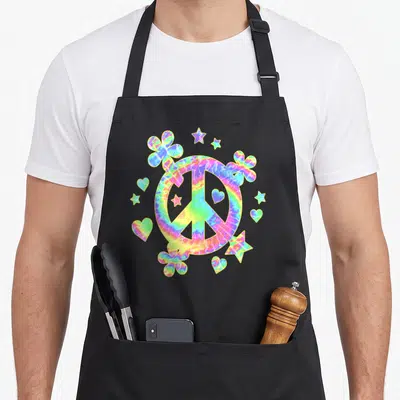 Tablier de cuisine noir avec panneau de paix tie-dye, fleurs, cœurs et étoiles colorées.