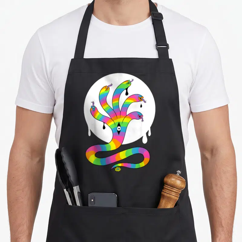 Tablier de cuisine noir avec illustration serpent arc-en-ciel à plusieurs têtes et œil au centre sur fond blanc circulaire.