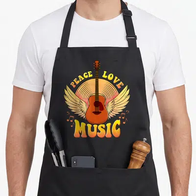 Tablier de cuisine noir avec une guitare aux ailes et les mots Peace Love Music en lettres colorées.