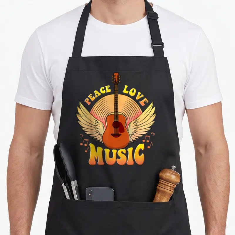 Tablier de cuisine noir avec une guitare aux ailes et les mots Peace Love Music en lettres colorées.