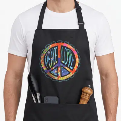 Tablier de cuisine noir avec un grand signe de la paix multicolore affichant les mots Peace Love en typographie ondulée et texturée.