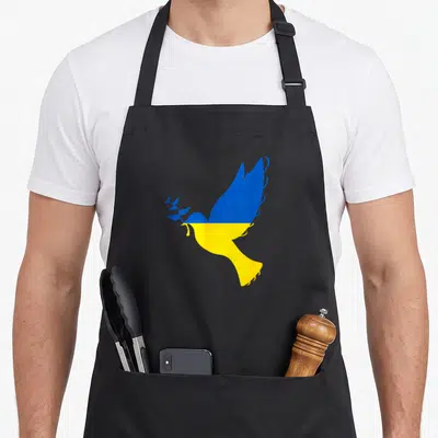 Tablier de cuisine noir avec colombe bleue et jaune tenant une branche d'olivier stylisée.