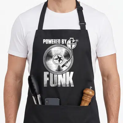 Tablier de cuisine noir avec illustration blanche d'un tourne-disque et le texte Powered By Funk en typographie usée.