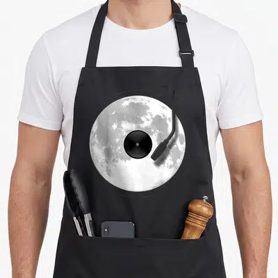 Tablier de cuisine noir avec illustration d'une platine vinyle posée sur une lune en nuances de gris.