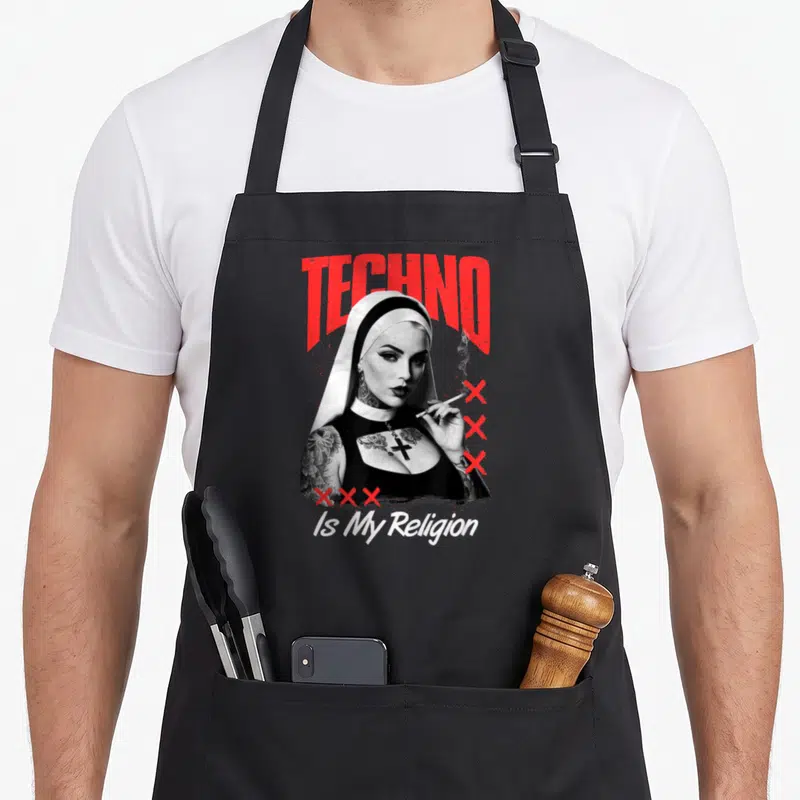 Tablier de cuisine noir avec une nonne tattooée fumant et le texte TECHNO Is My Religion en rouge et blanc.