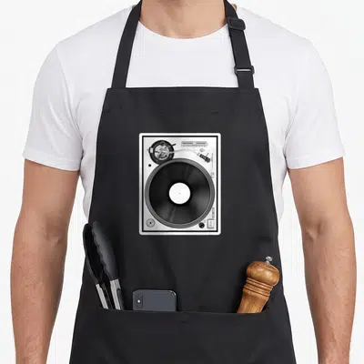 Tablier de cuisine noir avec une grande illustration blanche représentant une platine vinyle de style DJ en vue de dessus.