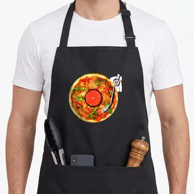 Tablier de cuisine noir avec une pizza dessinée comme un disque vinyle DJ et un bras de lecture blanc.