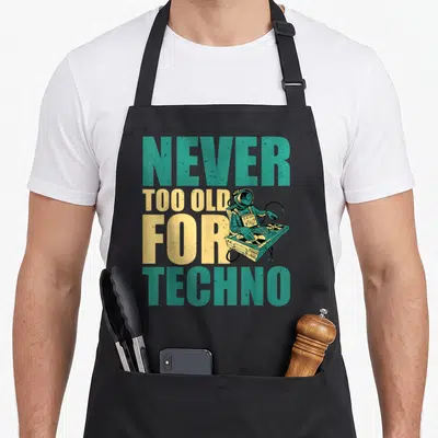 Tablier de cuisine noir avec un astronaute DJ et le texte Jamais trop vieux pour Techno en lettres colorées.