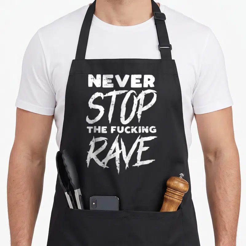 Tablier de cuisine noir avec l'inscription blanche « Never Stop The Fucking Rave » en style graffiti.