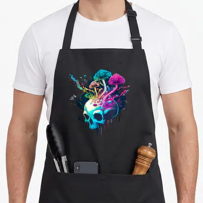 Tablier de cuisine noir avec un crâne stylisé et des champignons aux couleurs vives sortant du sommet.